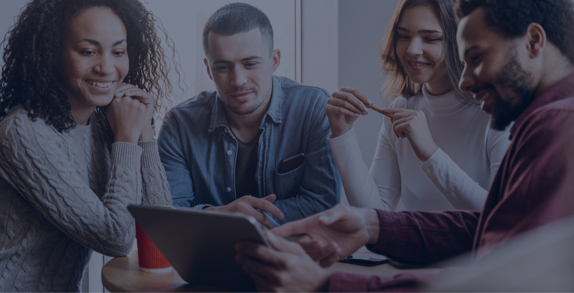 Quatro pessoas sorridentes analisando informação em tablet